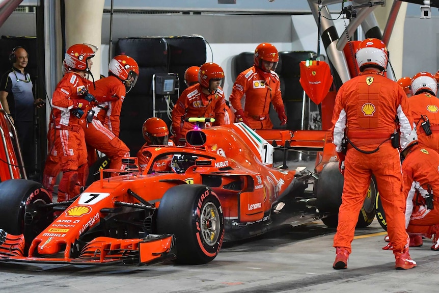 Formula 1 driver Kimi Raikkonen's car in the pits surrounded by mechanics