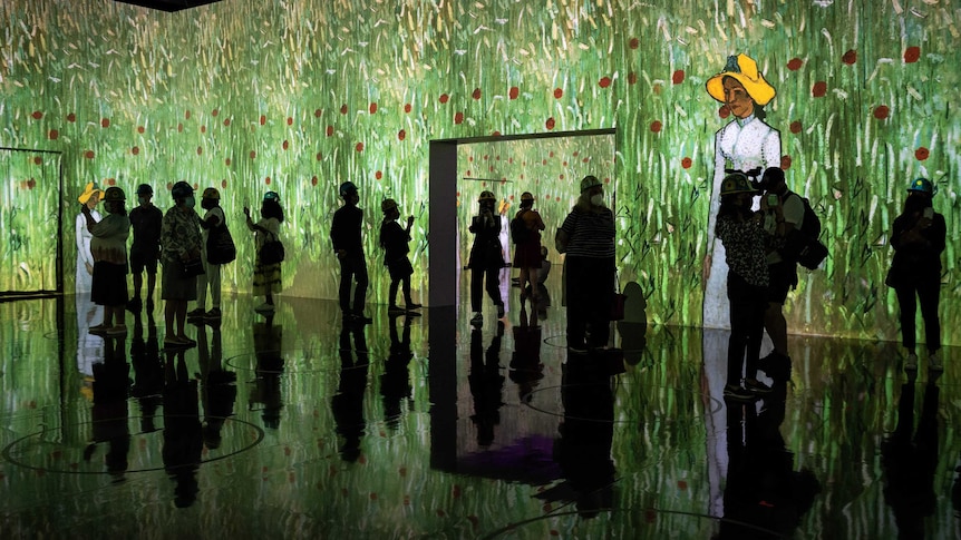 silhouted people in a large otherwise empty room, with Vincent van Gogh's work projected on the walls around them