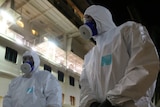 Two men in hazmat suits on a ship