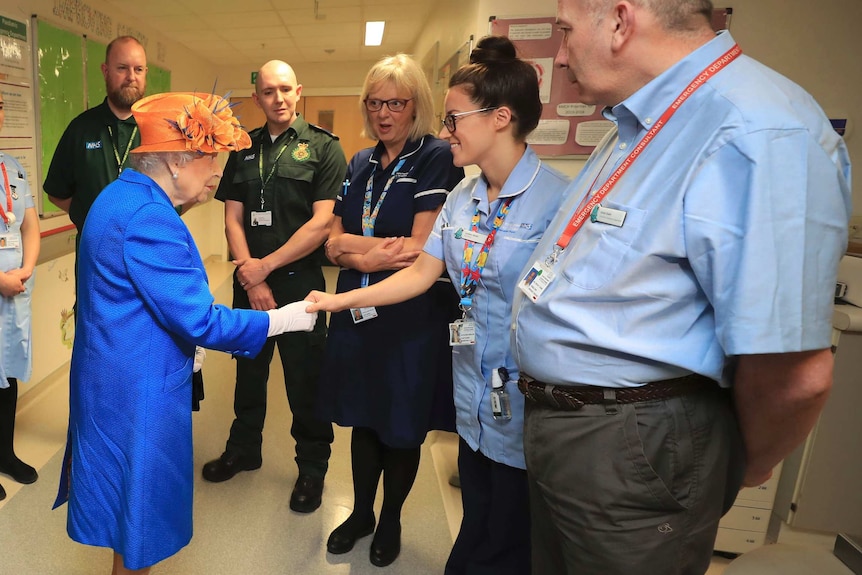 Queen Elizabeth II speaks with hospital personnel as she visits the Royal Manchester Children's Hospital