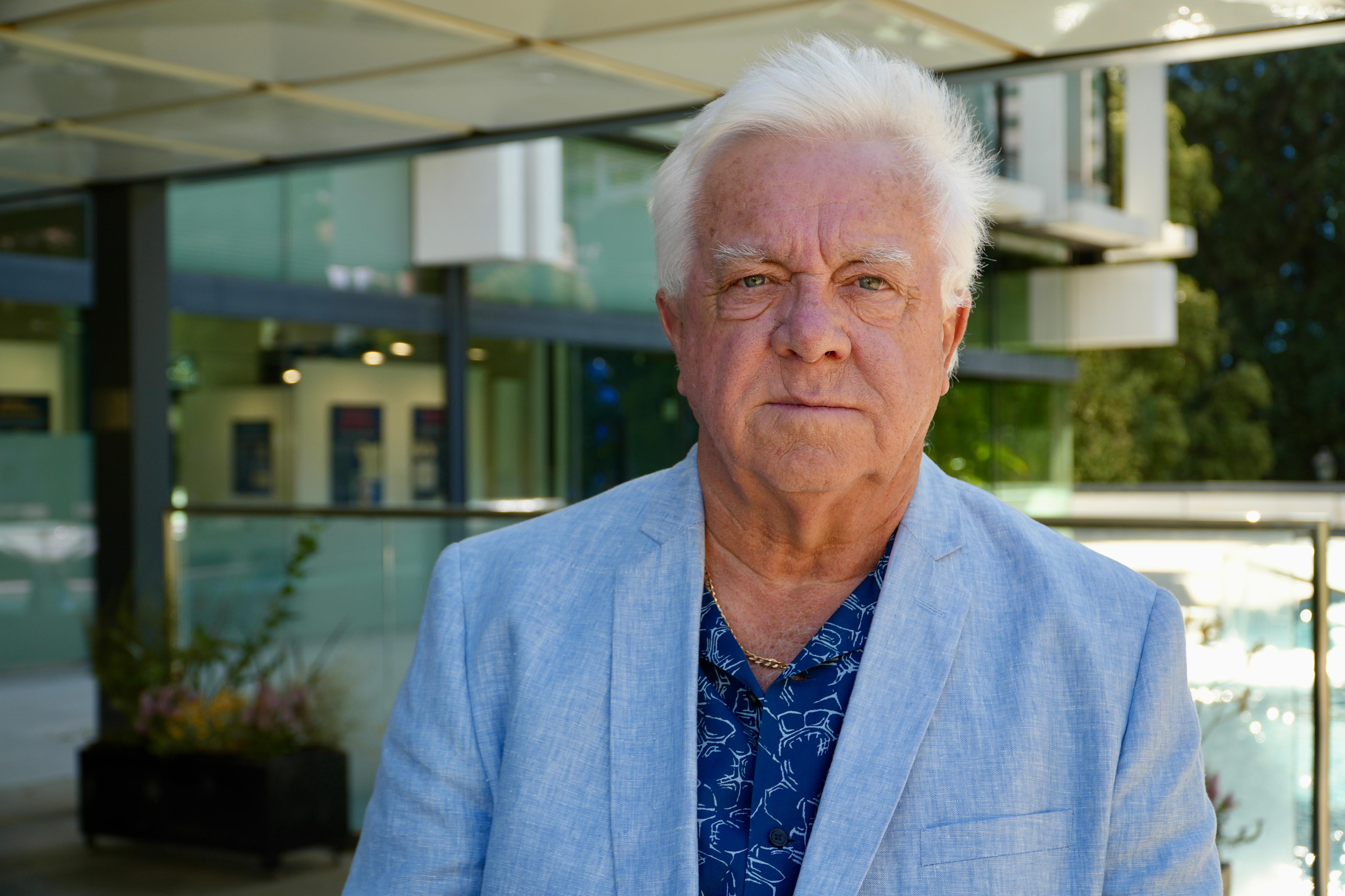 Un hombre de pelo blanco y chaqueta azul claro.