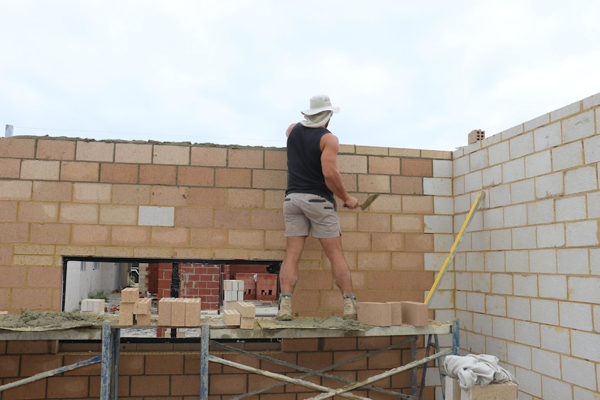 A bricklayer works on a home.