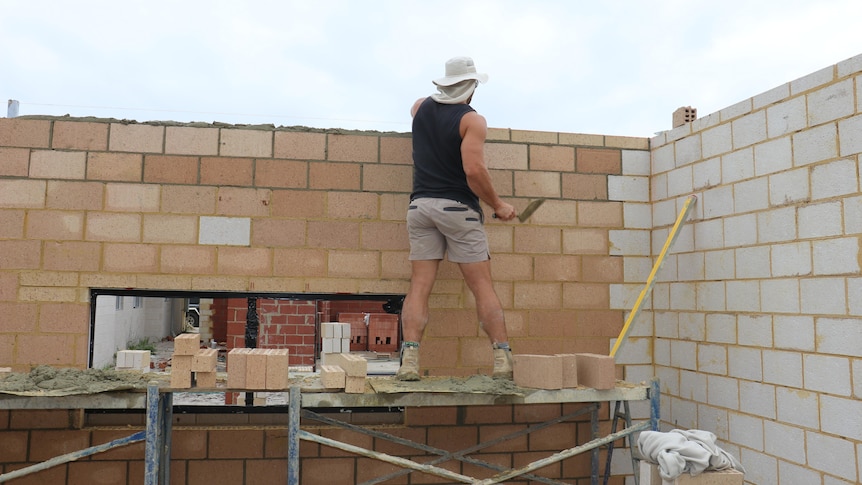 A bricklayer works on a home.