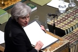 Theresa May looks over her shoulder while speaking in parliament.