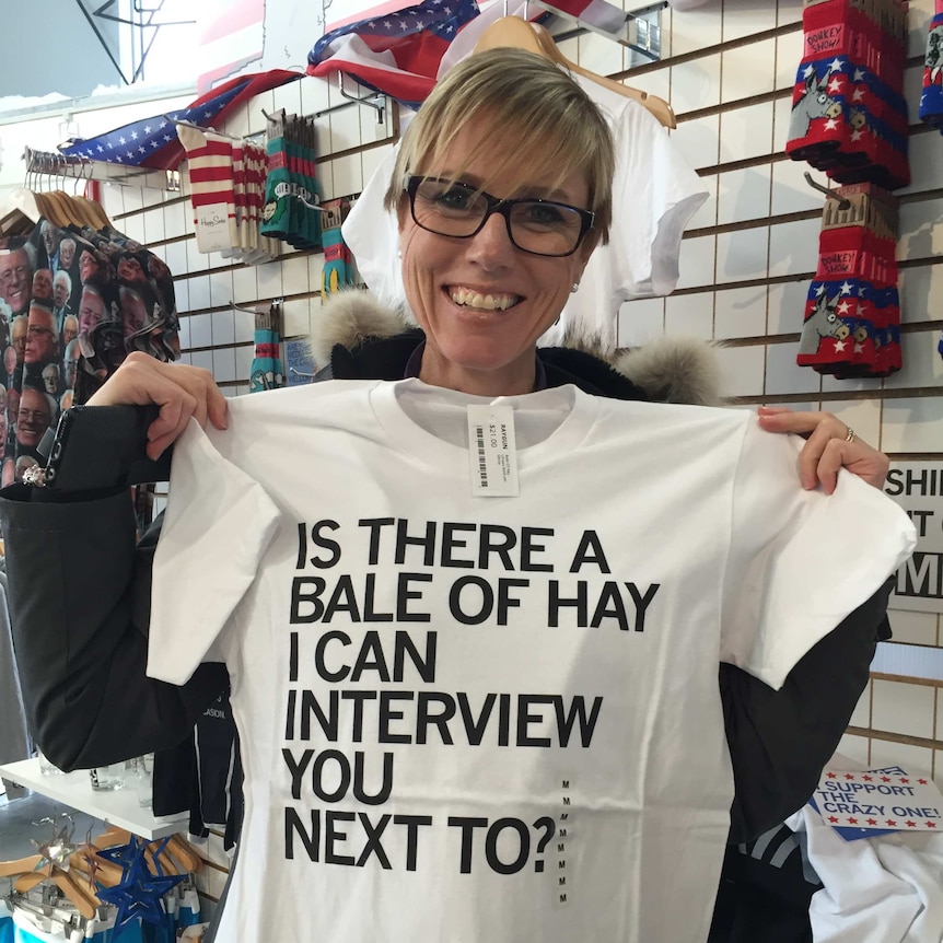 Zoe Daniel holds t-shirt with 'is there a bale of hay I can interview you next to" written on it