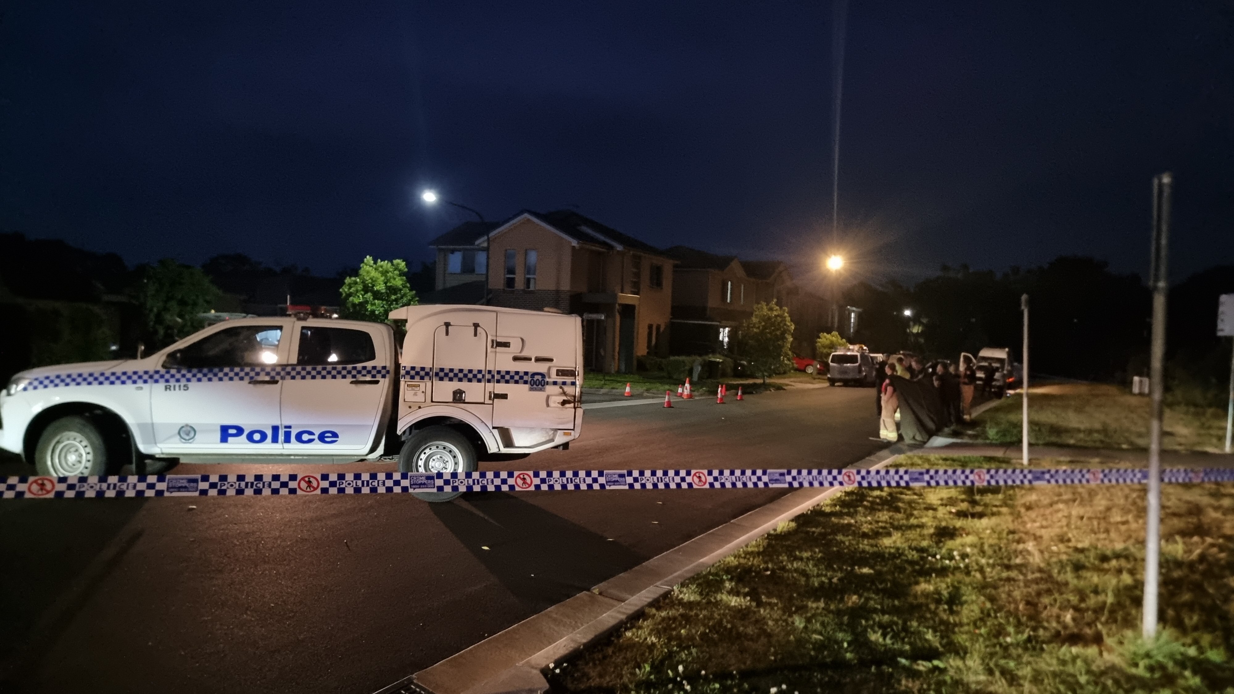A police truck on a road with police tape, at night.