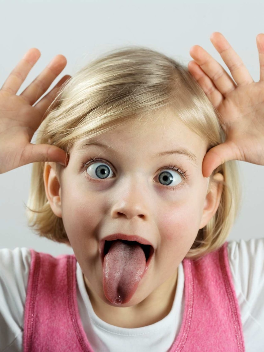 A young girl sticks her tongue out to make a funny face.