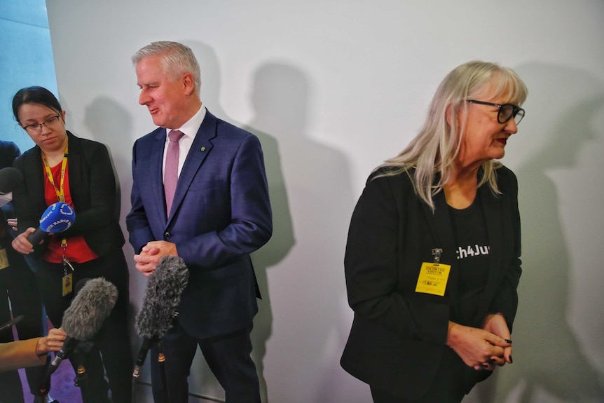 A man and a woman speak in a corridor