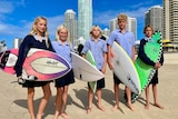 students in school uniform standing on Surfers Paradise beach with their surfboards