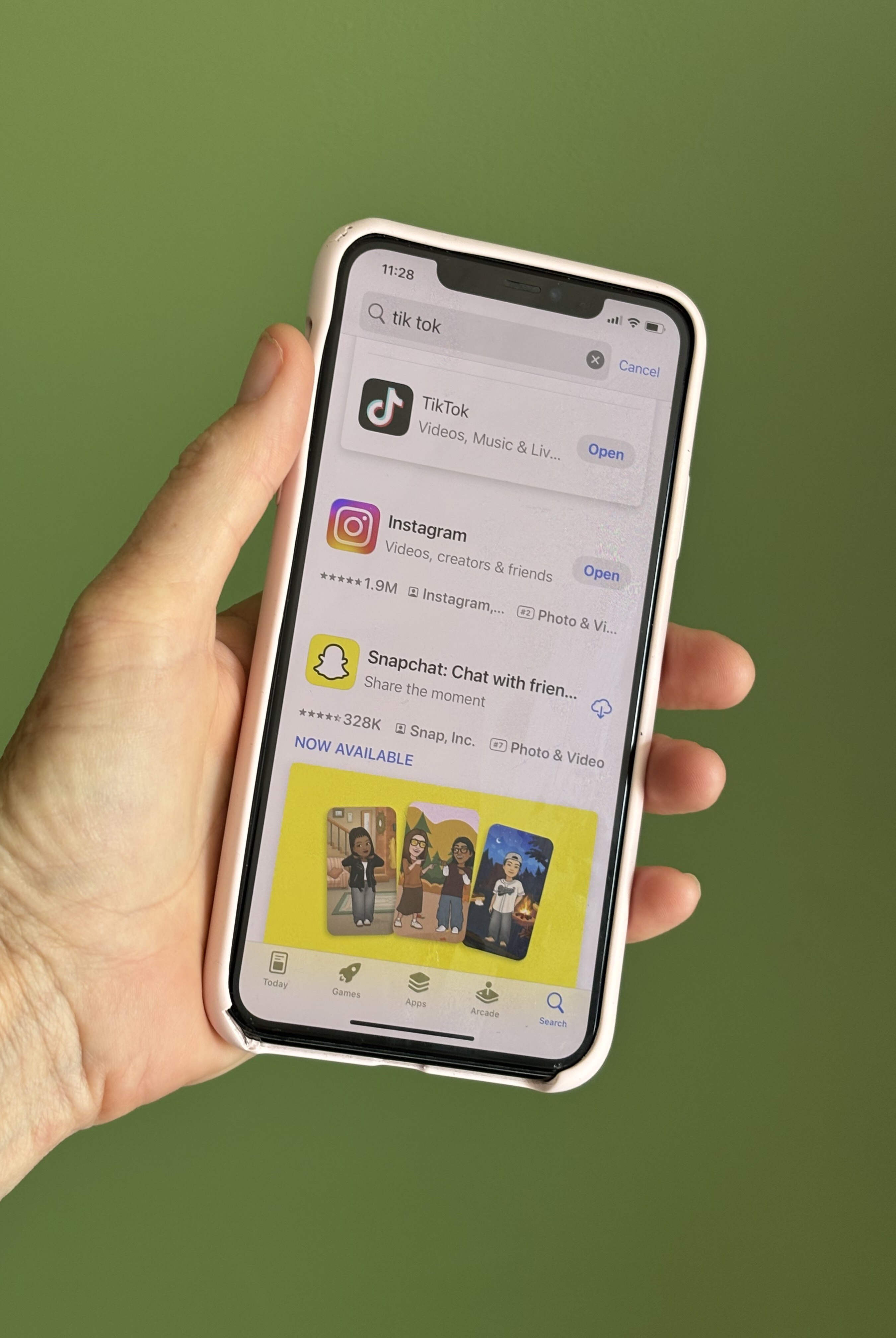 Primer plano de una persona que sostiene un teléfono móvil, usando TikTok, Instagram y Snapchat sobre fondo verde.