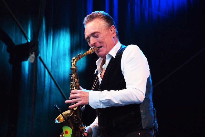 Brian Travers plays the saxophone on stage.