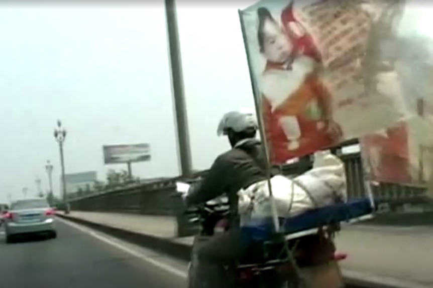 A motorbike with a flag printed with an image of a child.