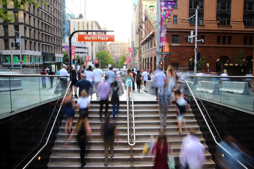Crowds of people walk from the Martin Place station in central sydney.