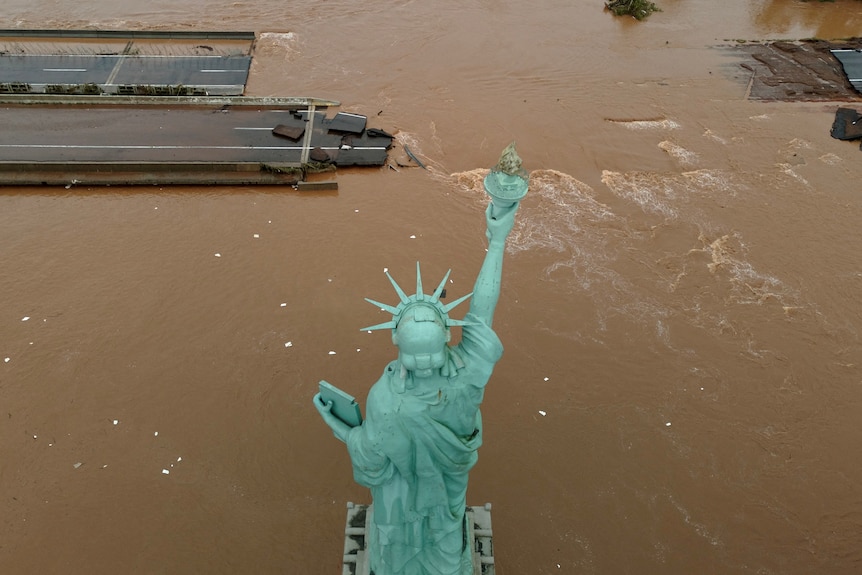 A statue of liberty in front of flood waters over a road. 