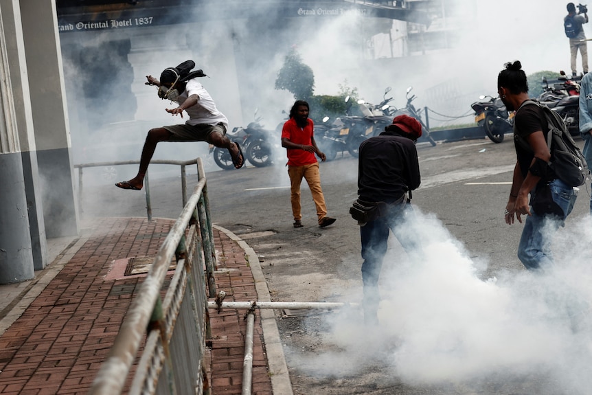 A group of men on a street try to escape tear gas.