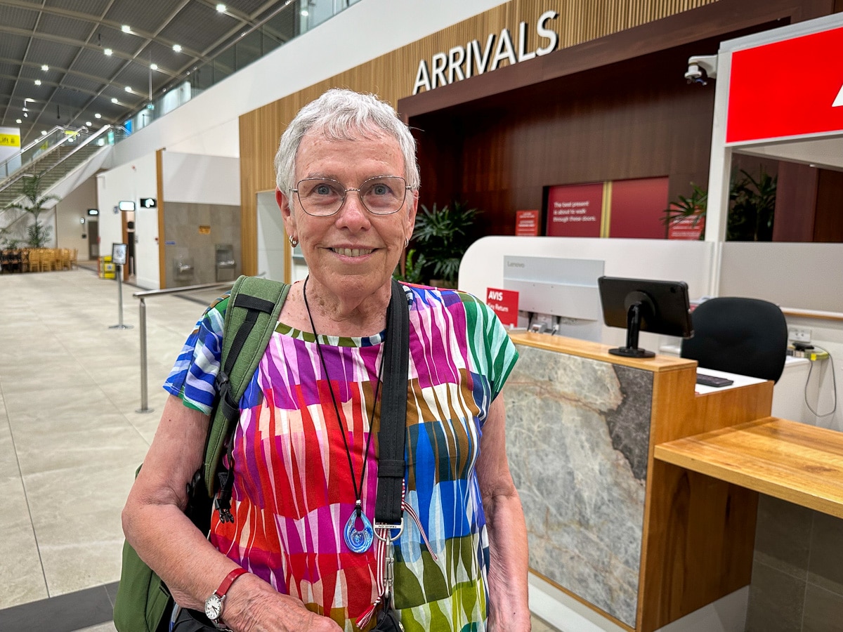 Uma mulher com uma camisa tingida sorri. 