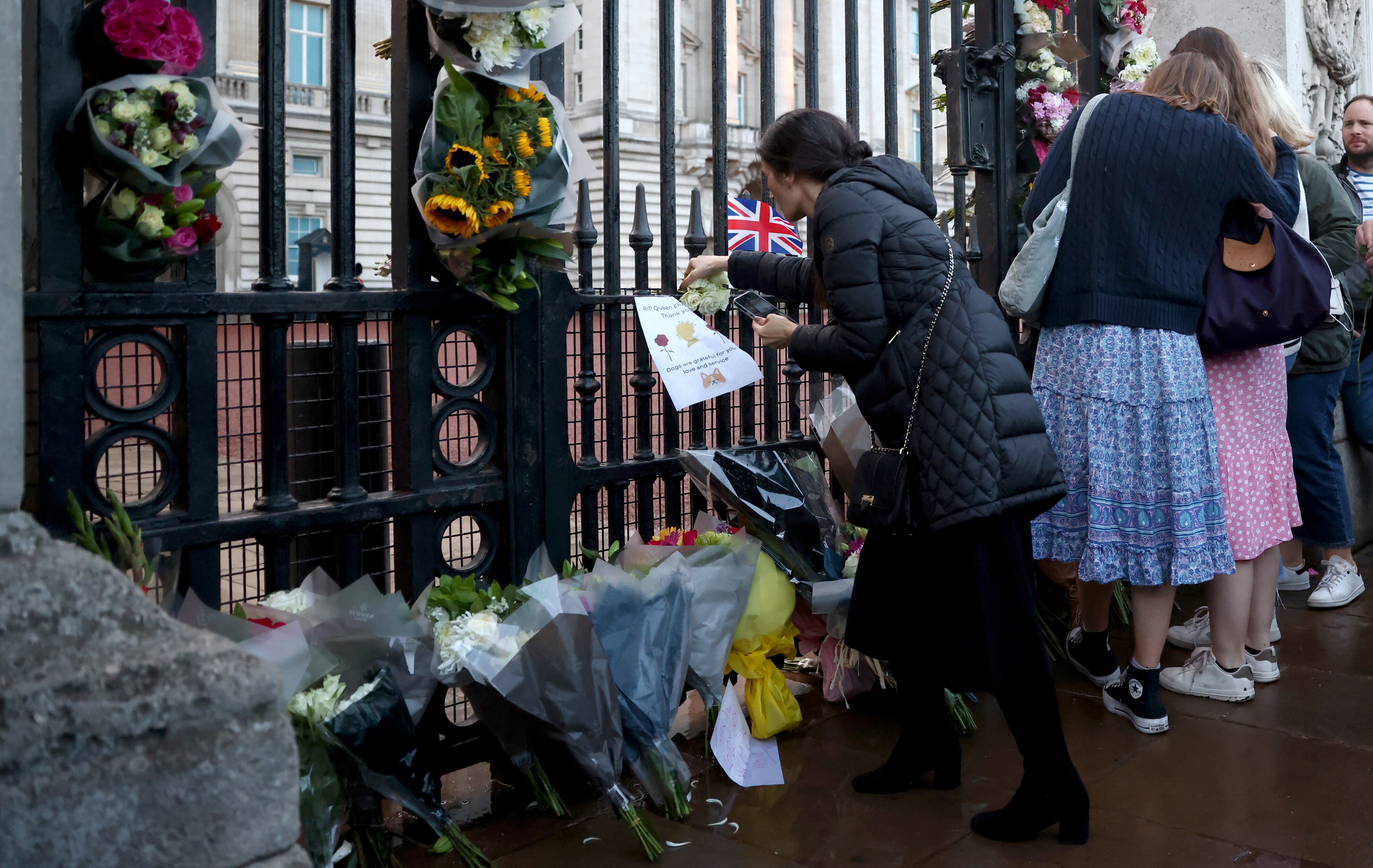 A person places flowers outside Buckingham Palace.
