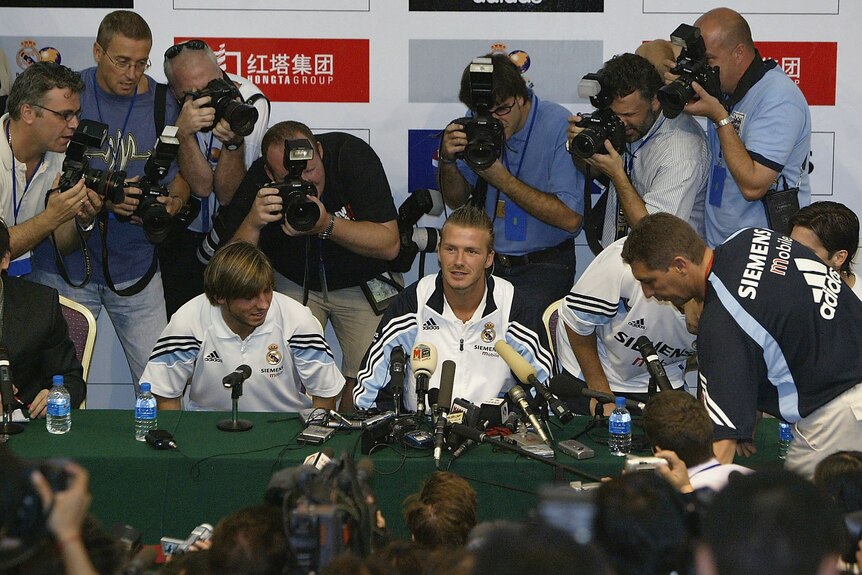 David Beckham has press and photographers surrounding him.