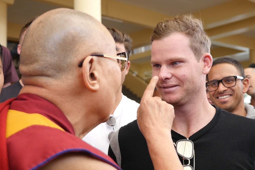 The Dalai Lama touches Steve Smith on the nose.