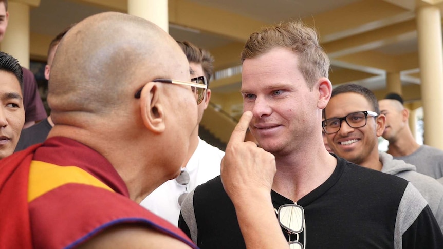 The Dalai Lama touches Steve Smith on the nose.