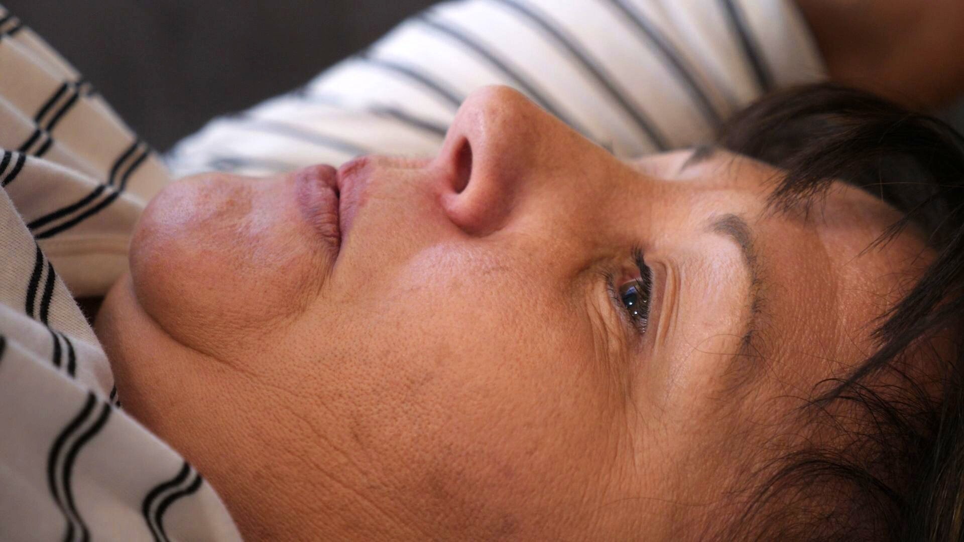 A close-up of a woman's face as she's breathing while lying on her back.
