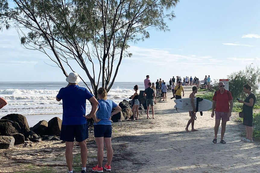 Crowd gathers to watch surf conditions at Kirra.