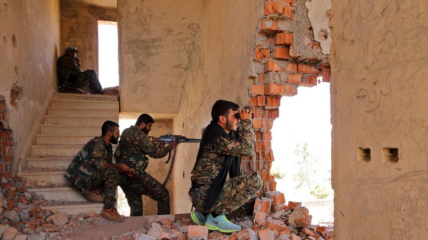 Kurdish fighters take up positions inside a damaged building in Hasakah, Syria