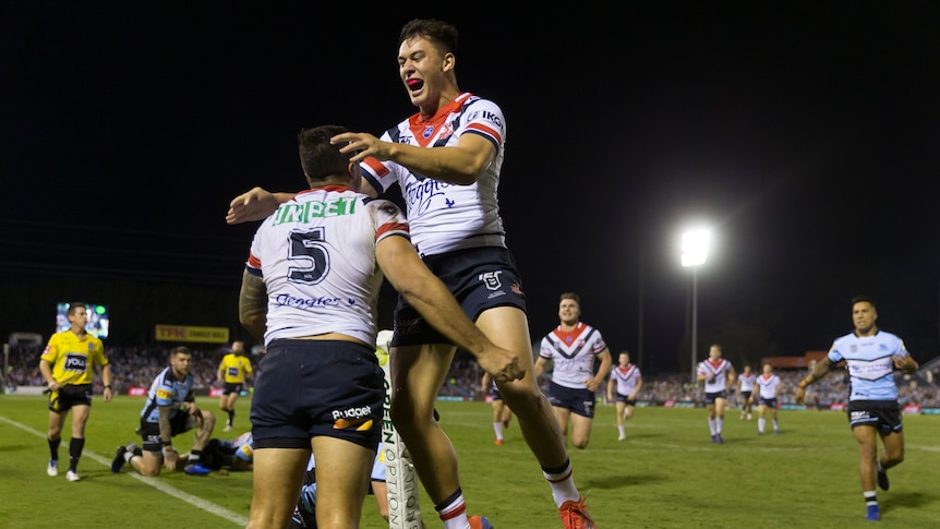 A rugby league player leaps into the arms of a teammate after a try is scored