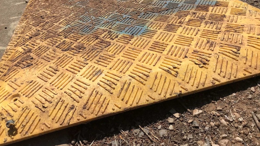 A yellow lid covering a pit on a footpath