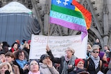 Women hold up signs in protest.