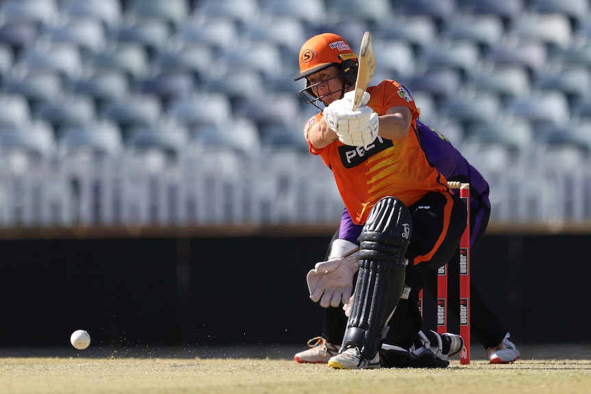 A Perth Scorchers WBBL batter drives the ball on one knee.