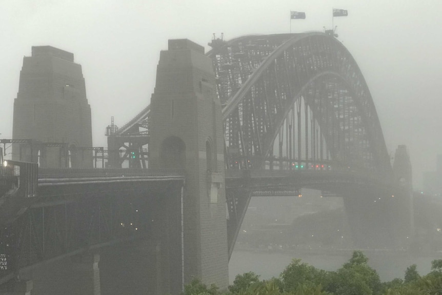 The Sydney Harbour Bridge stands amid a grey sky as torrential rain batters the city.