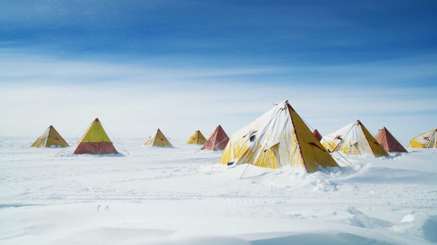 A series of red and yellow pyramid-shaped tents in the snow