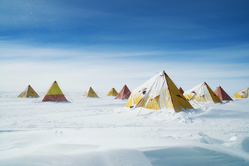 A series of red and yellow pyramid-shaped tents in the snow