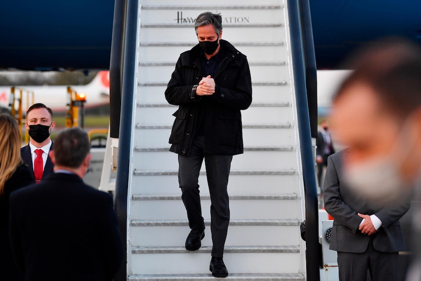 Antony Blinken walks down stairs from an aeroplane.