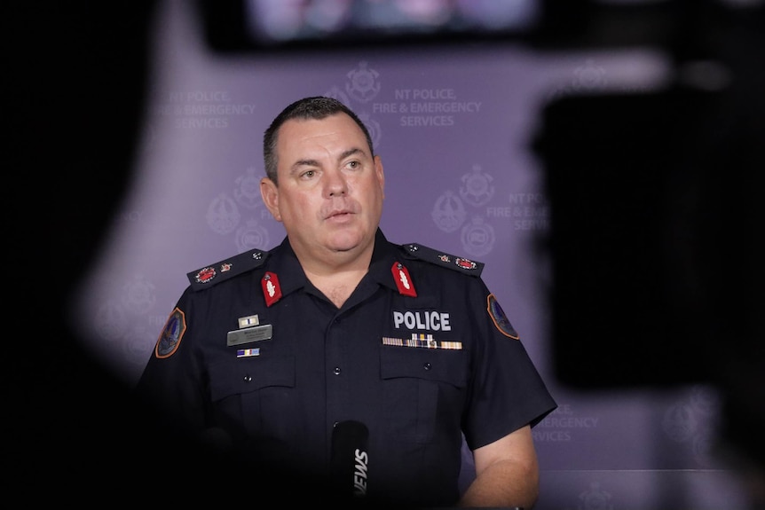 A man wearing police uniform speaking in a press briefing room.