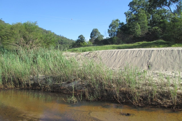 Piles of sand next to a river