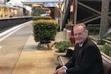 Fred sitting at a train station.