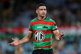 A South Sydney NRL player holds his arms out in question during a game.