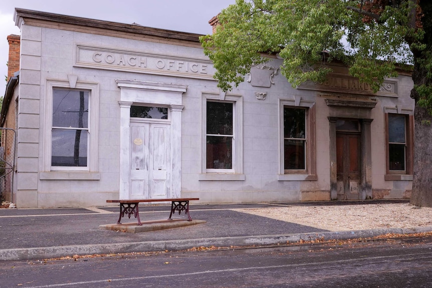 A old building with a seat in front of it.
