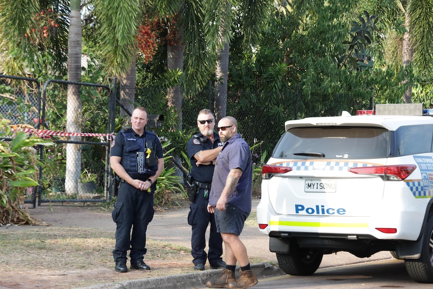 police officers standing by a car outside a home