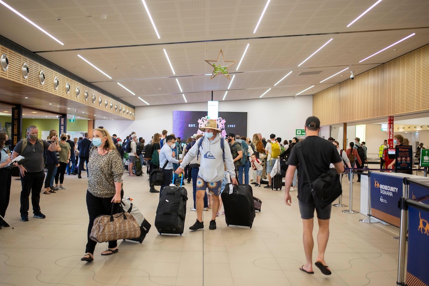 Passengers walk through the arrivals area of an airport