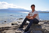 Saroo Brierley sits on a rock in front of the sea