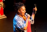 A woman on stage speaks into a microphone