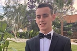 A teenage boy smiles for a photo while wearing a suit.