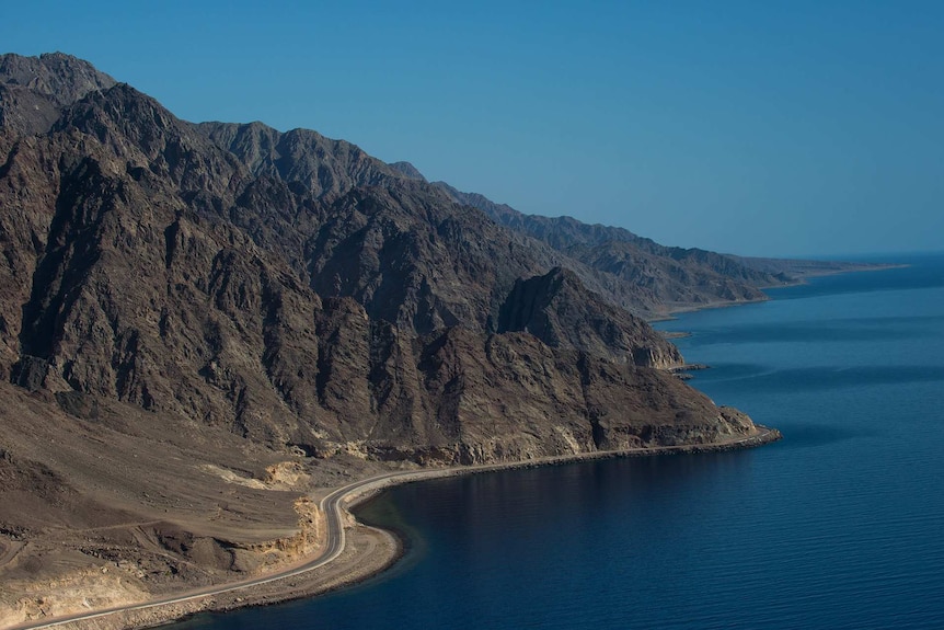 A road wraps around a rocky coastline in Saudi Arabia.