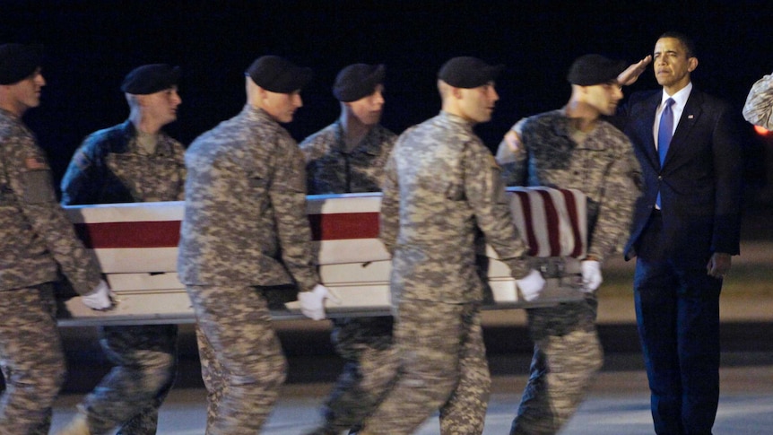 Six US soldiers carry a coffin past Barak Obama, who stands in salute.