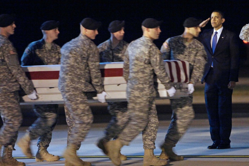 Six US soldiers carry a coffin past Barak Obama, who stands in salute.