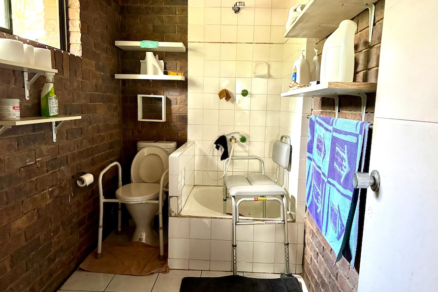 A small bathroom in a rural home with basic mobility aids for aged care.