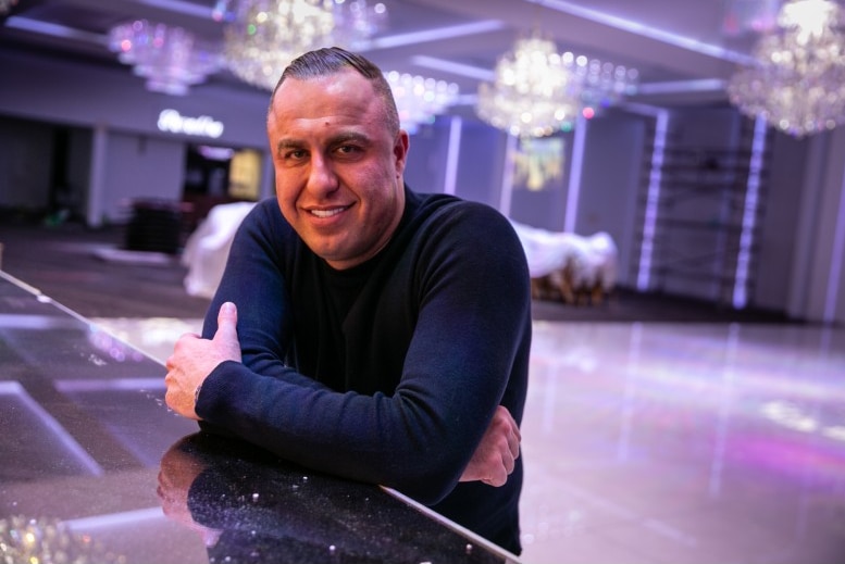 A man smiling  in an empty function room.